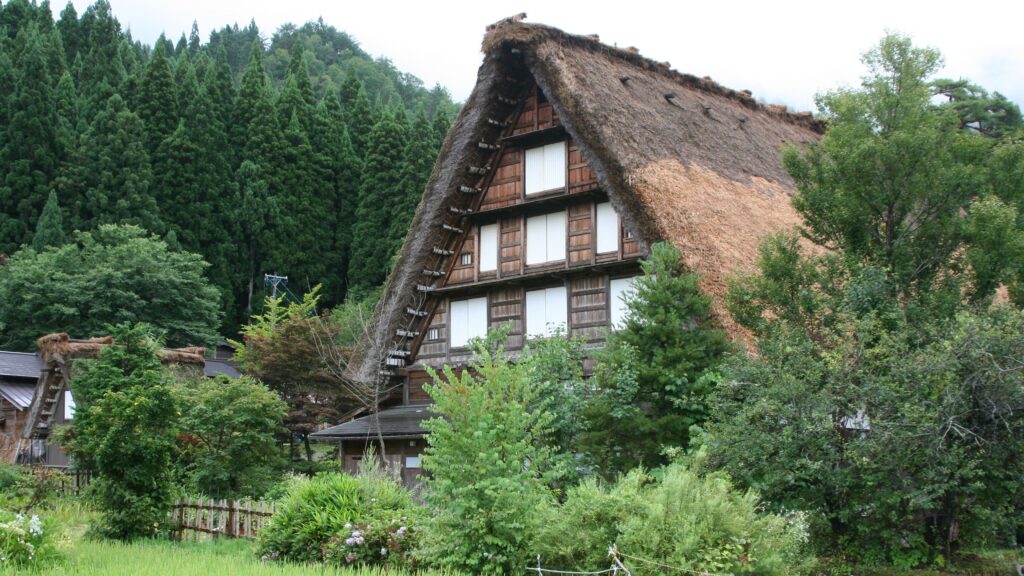 Akiya Explained: Japan's 9 Million Vacant Homes Decoded A rustic thatched roof house surrounded by lush greenery in Nanto, Toyama, Japan.