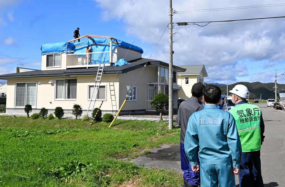 Inspecting a Japanese house for roof damage and water leaks after a typhoon has passed.